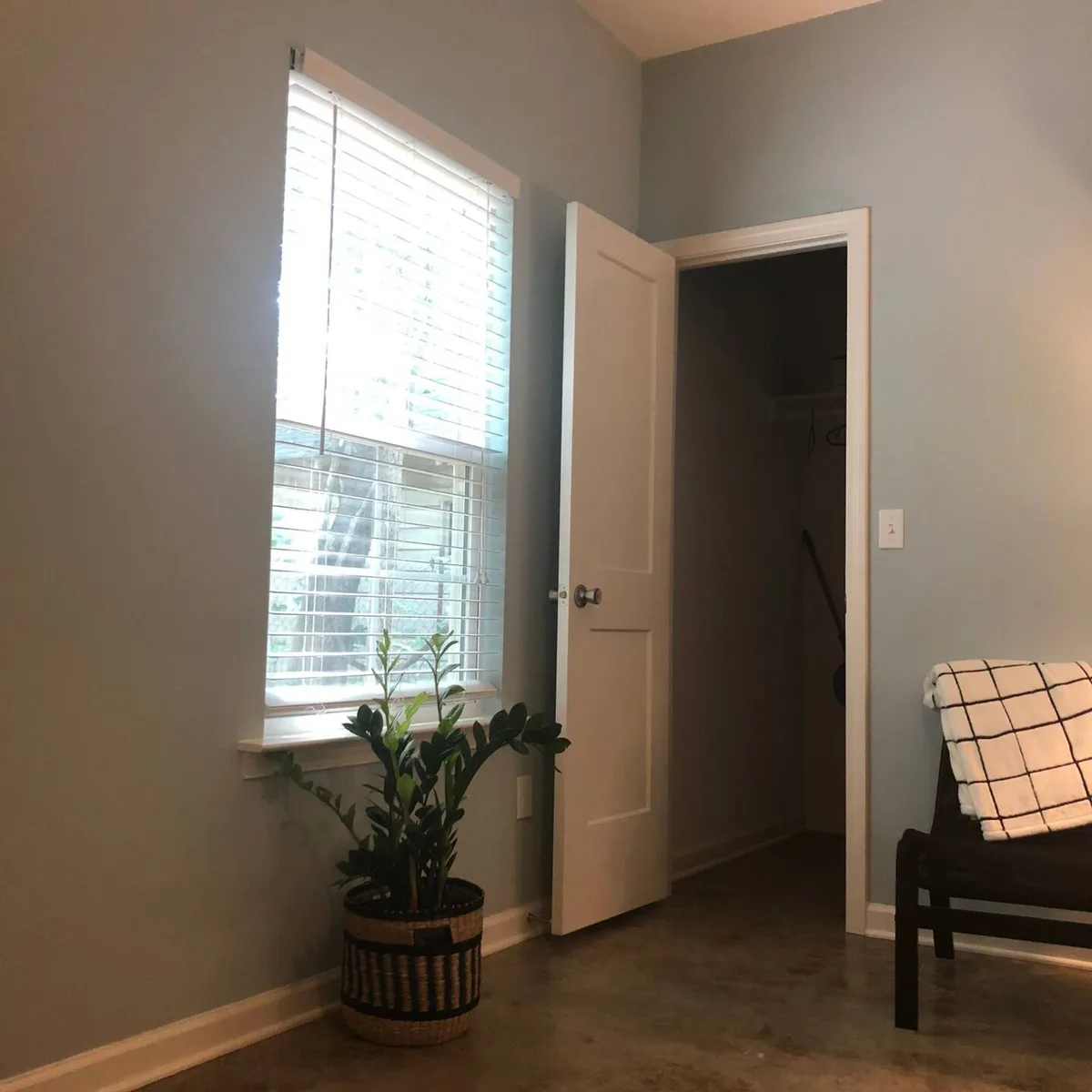 This interior image shows a tranquil entry nook with a window, indoor plant, closet, and woven basket—suggesting a smooth, organized transition as guests move from arrival into their private space.