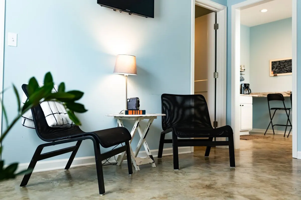This cozy corner features two black chairs, a small white table, a lamp, and a retro radio, creating a relaxed setting ideal for planning outings or unwinding after an exciting night. The space feels inviting and social, perfect for guests preparing for an evening in Overton Square or sharing stories after their adventures.